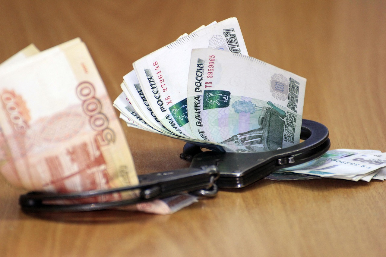 Наручники лежат на денежных купюрах — символ борьбы со взятками