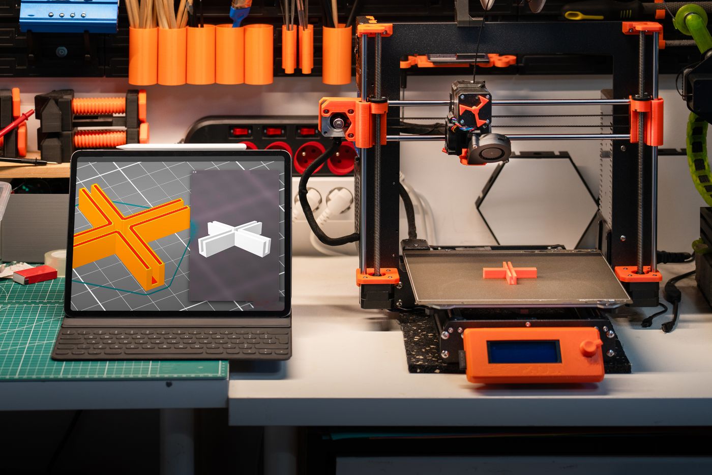Рабочее место с 3D-принтером и монитором, на котором открыты 3D-модели деталей