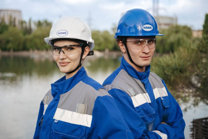 Двое инженеров в защитных касках и очках на промышленном объекте