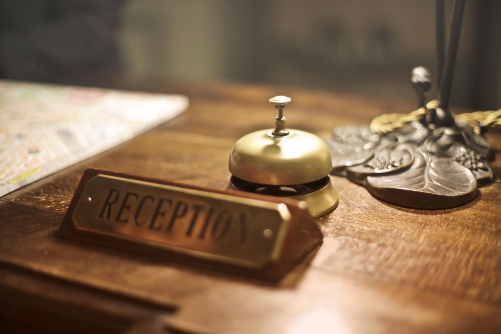 Латунный звонок и табличка Reception на деревянной стойке гостиницы