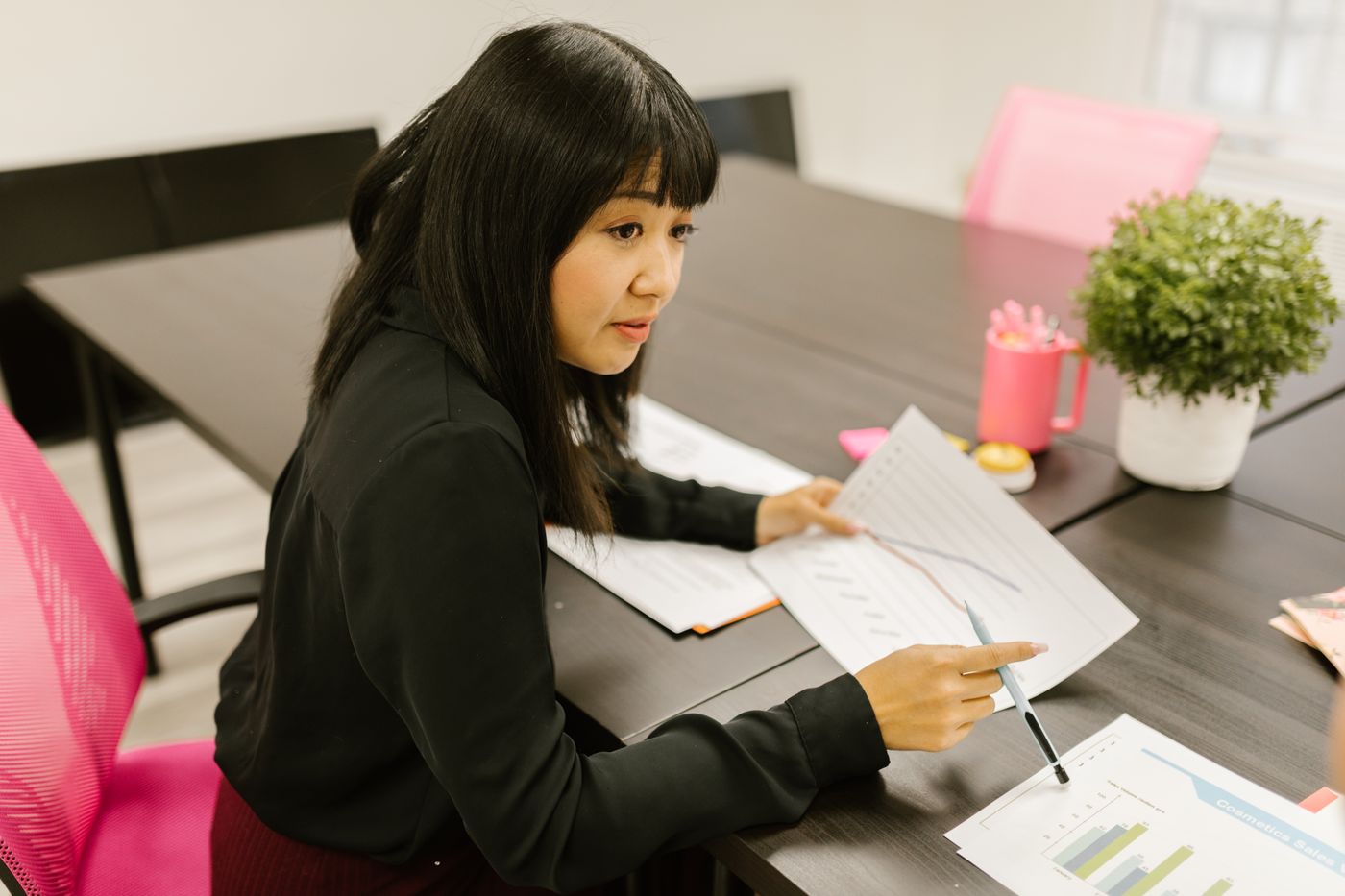 Молодая девушка в деловом костюме изучает графики в папке за офисным столом