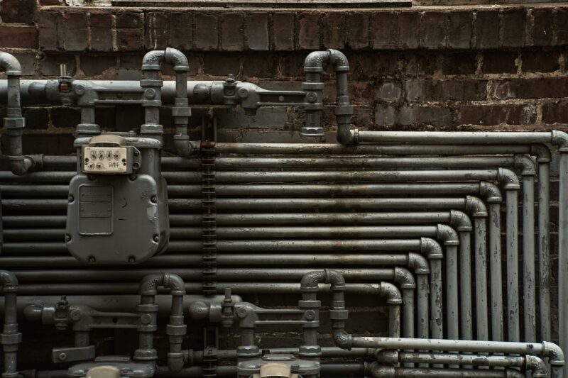 Стальные трубы и газовый счётчик на кирпичной стене здания