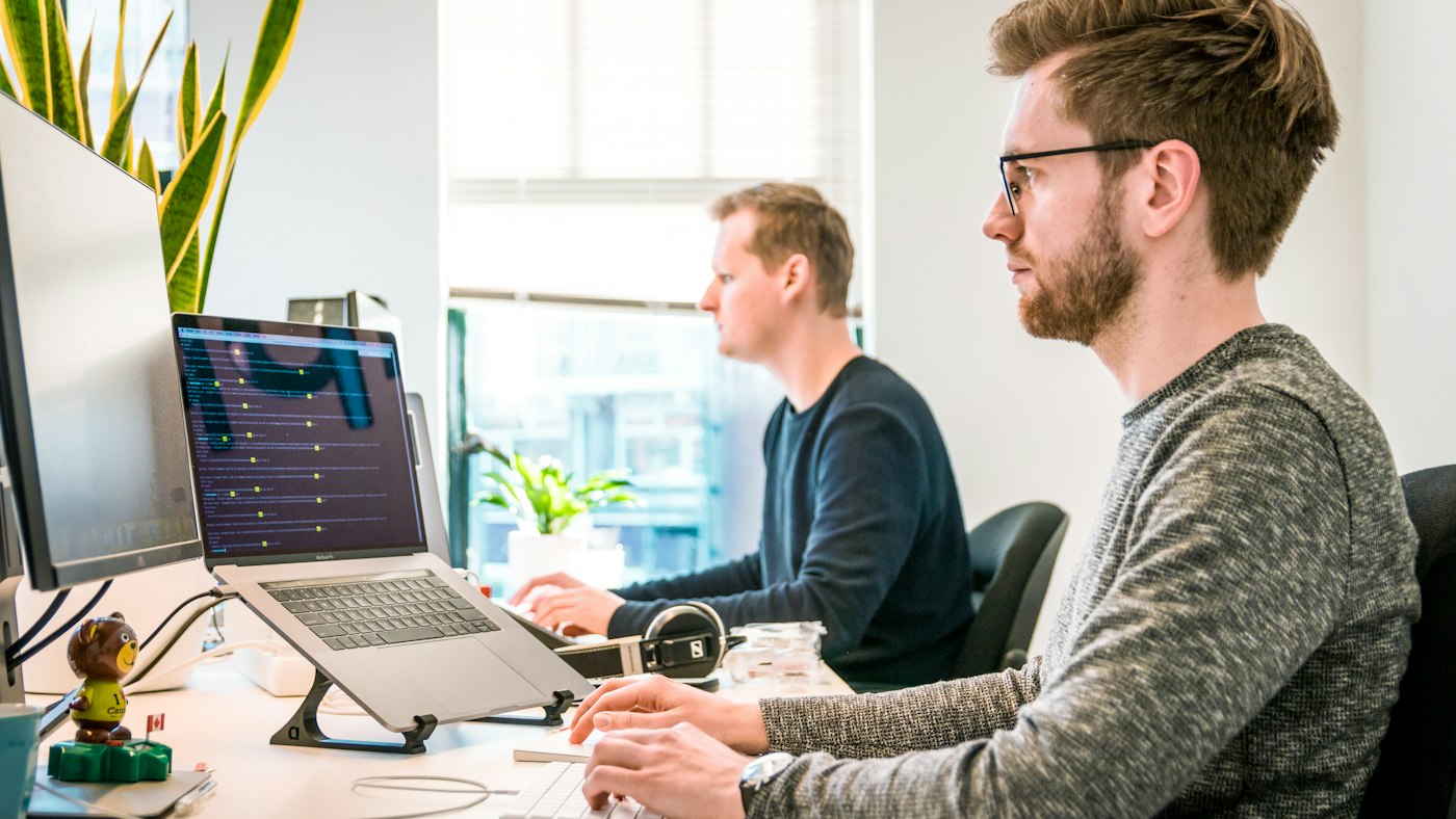 Разработчик печатает на клавиатуре за компьютером в офисе IT-компании