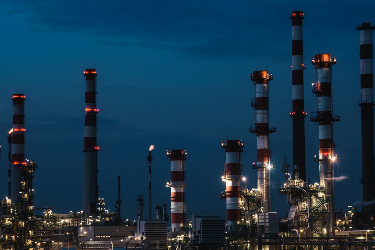 Красно-белая башня нефтеперерабатывающего завода в ночном освещении