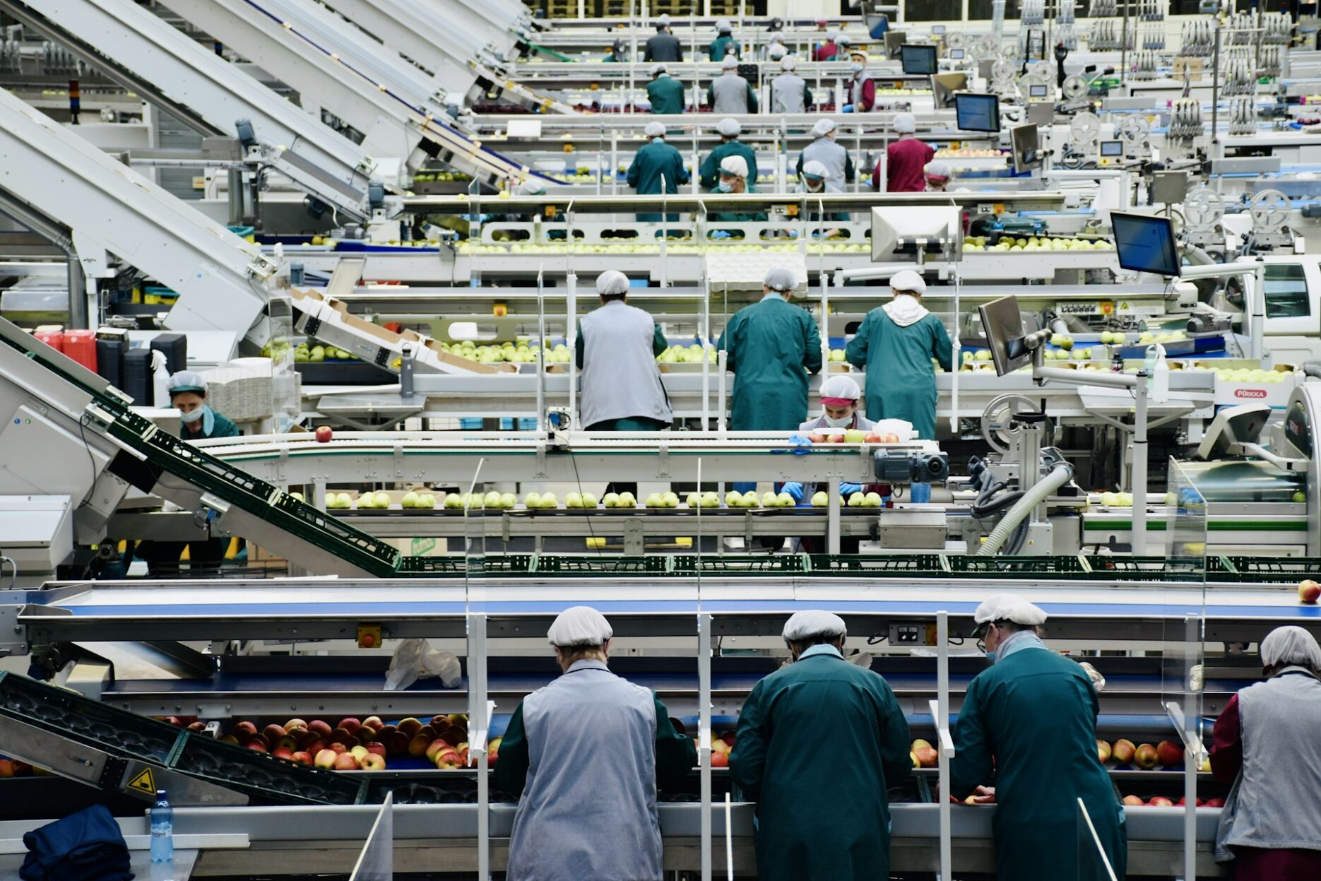 Работники в цехе предприятия по переработке яблок у производственной линии