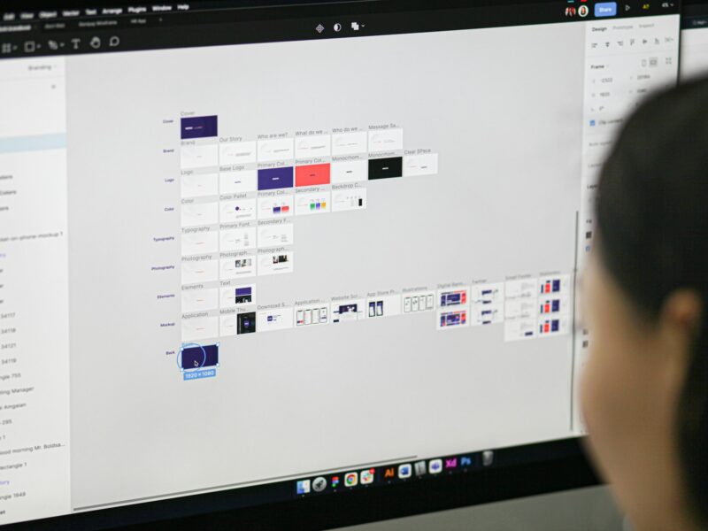 Дизайнер интерфейсов работает над макетом в Figma на большом мониторе