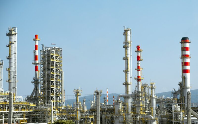 Красно-белые трубопроводы и технологические аппараты на территории нефтеперерабатывающего завода
