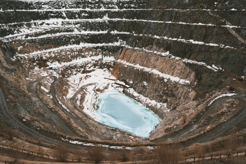 Открытый карьер Коктокай на Алтае с уступами бортов и водой на дне, вид с высоты