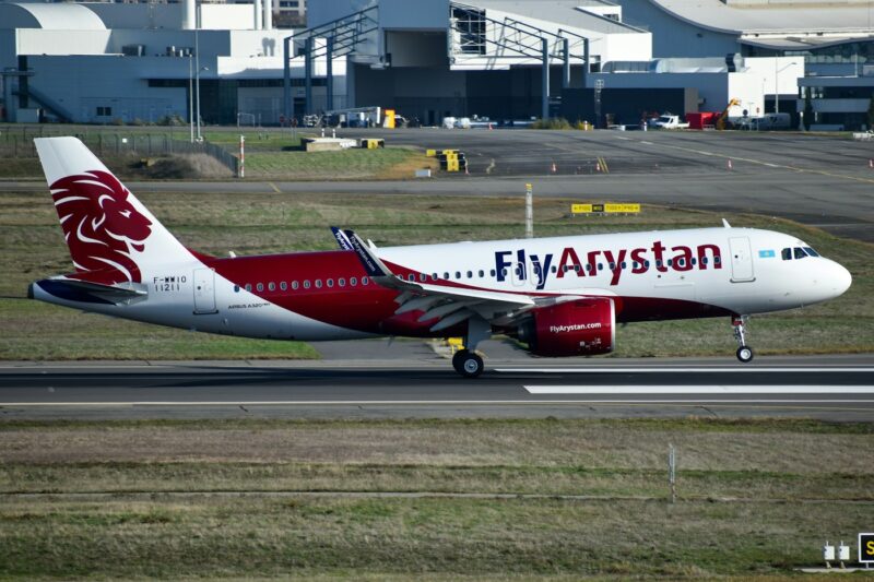 Самолёт Airbus казахстанской авиакомпании FlyArystan в бело-красной ливрее на взлётной полосе