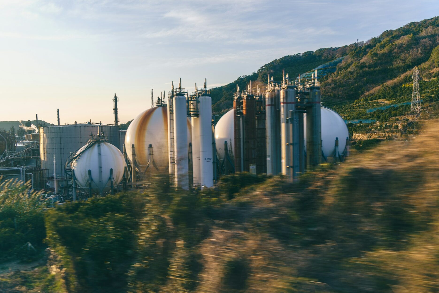 Сферические резервуары и технологические башни нефтехимического предприятия у лесистого холма в Японии
