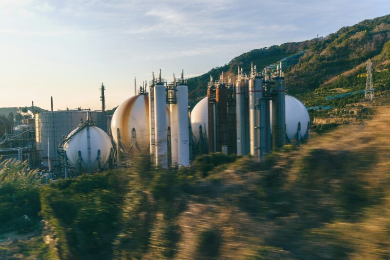 Сферические резервуары и технологические башни нефтехимического предприятия у лесистого холма в Японии
